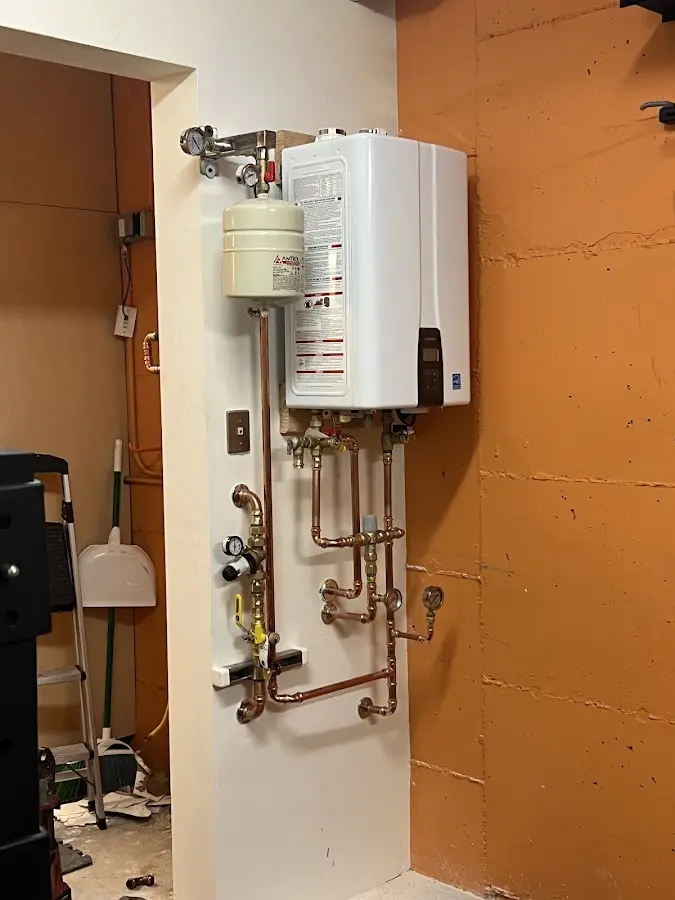Plumbing technician inspecting water heater connections in Plover